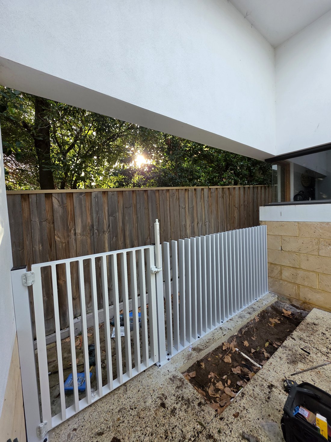 White aluminium batten fence and gate against a timber paling backdrop, South Perth WA