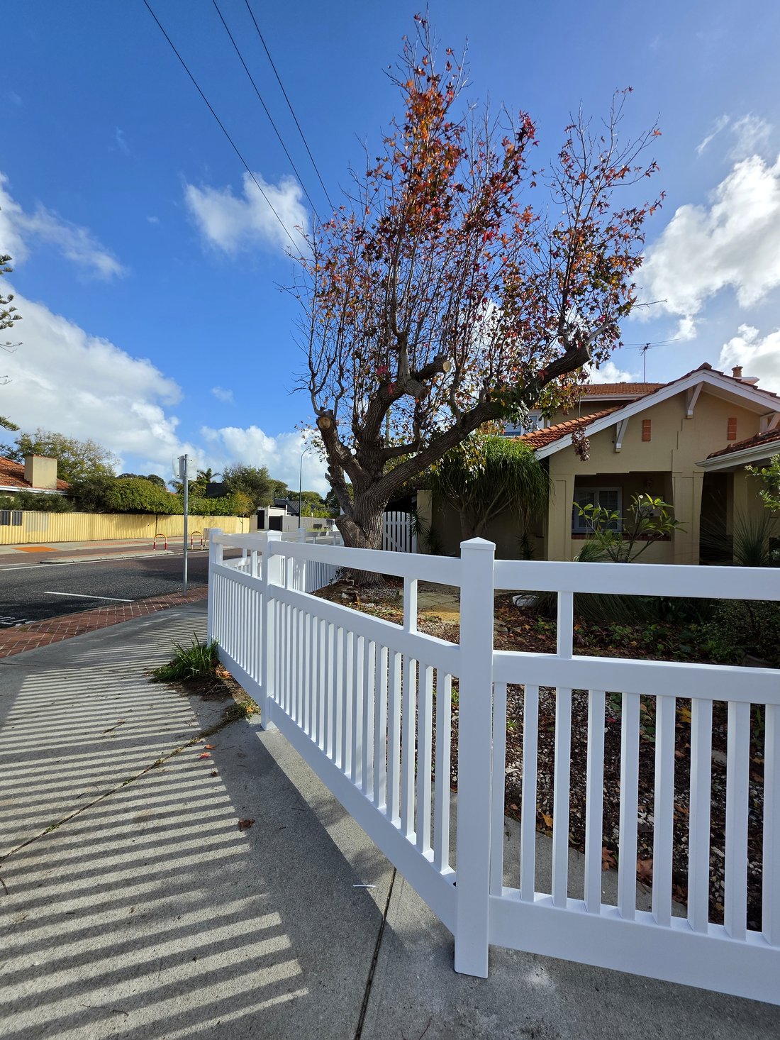 White PVC Hamptons picket fence with a character home and tiled roof behind, Perth WA