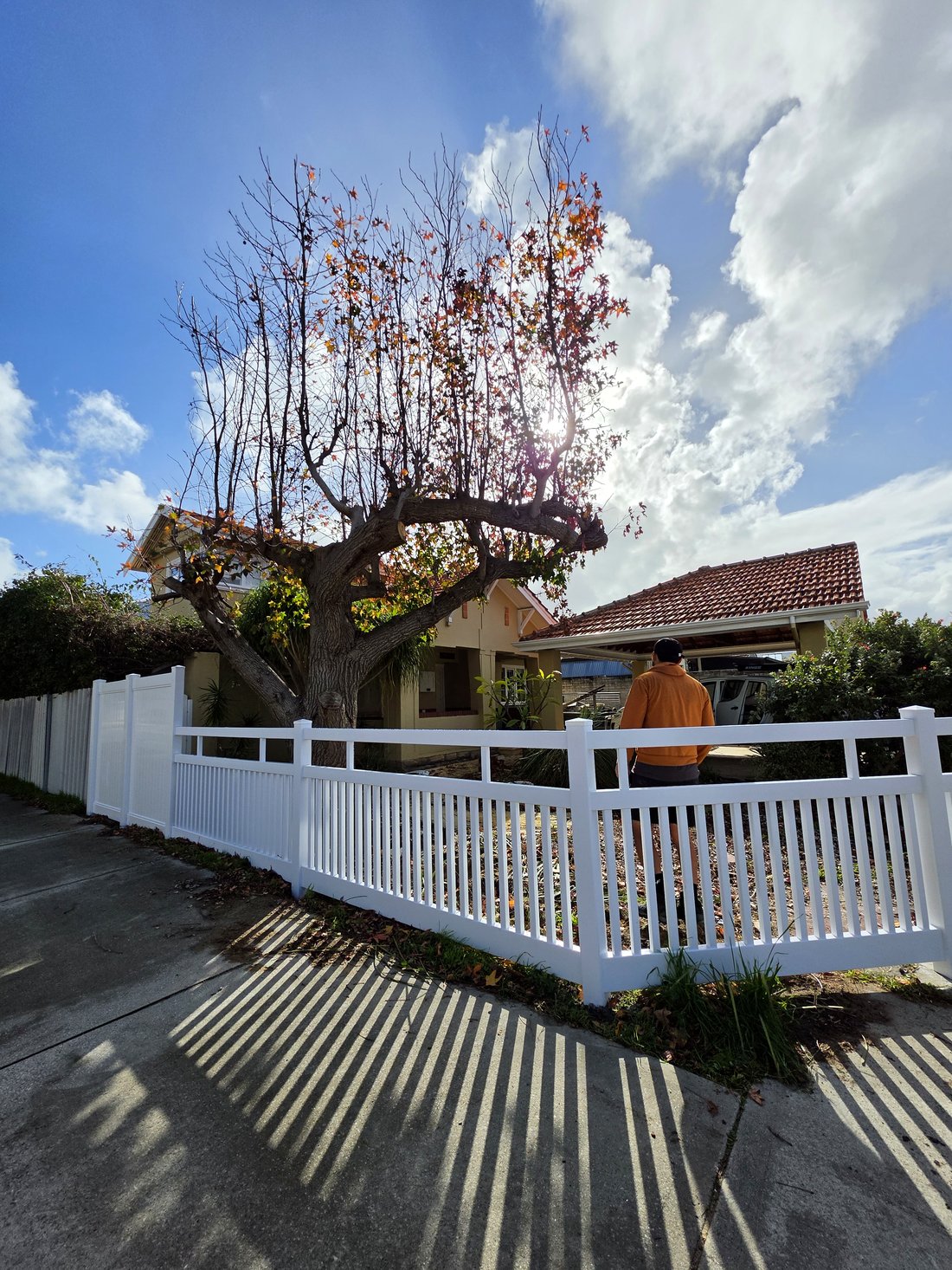 White PVC Hamptons picket fence with the property owner reviewing the finished job, Perth WA