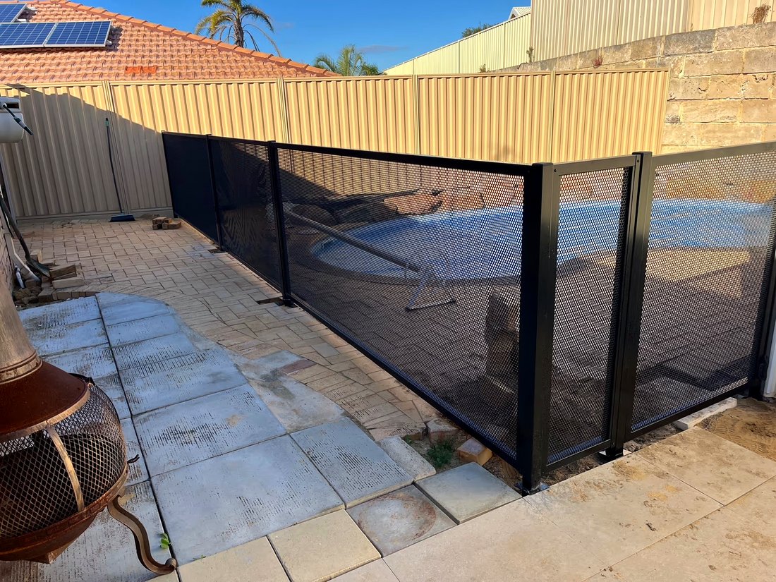Close view of black perforated pool fencing panels with the pool visible behind, Currambine WA